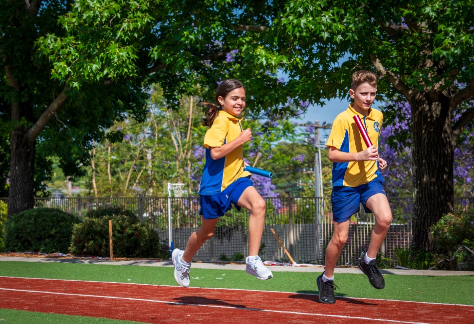 Students run a relay on a school athletics track.